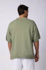Remera de tejido de punto liviano en color verde oliva, con corte oversize, cuello redondo acanalado y mangas cortas con terminación en rib.