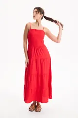 Vestido largo color blanco, confeccionado en lino, con tiras finas regulables, escote recto y falda amplia de corte acampanado con volados escalonados.