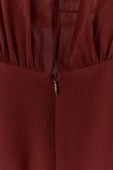 Vestido largo fluido en color bordó, confeccionado en georgette. Presenta cuello redondo, mangas largas con pliegues terminadas en puños y tiras ajustables para atar en la cintura. Incluye forro interior a tono.
