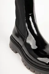 Bota corta negra de símil cuero, con punta redonda, laterales elastizados y suela tipo tractor de 5 cm de alto.