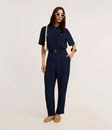 Camisa color fucsia de tejido airflow, con cuello camisero, mangas cortas con pliegues, cierre frontal con botones metalizados y bolsillos con solapa en el pecho.