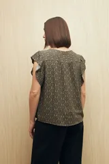 Blusa estampada con motivos de hojas en tonos beige y negro, con escote en V, botones al frente y volados en los hombros.
