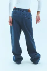 Pantalón de jean azul de corte babucha, tiro medio, con elástico en la cintura, bolsillos delanteros y logo bordado en amarillo en la pierna derecha.