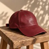 Gorro tipo visera color bordó de cuero, con ojales metálicos para ventilación y costuras pespuntadas en la visera.