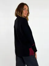 Sweater de punto color bordó con cuello en V, manga larga con puños acanalados y detalle de franja en contraste. Presenta un diseño holgado con aberturas laterales.