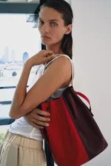 Bolso de hombro formato maxi de piel, en combinación de colores rojo y bordó. Cuenta con detalle de pespuntes, bolsillo interior con cremallera extraíble y cierre mediante fruncido con asas finas de hombro.