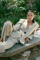 Blazer sastre de corte recto, color beige, con cuello solapa, hombreras marcadas y cierre frontal de dos botones oscuros. Cuenta con bolsillos con solapa en el frente y un bolsillo ojal en el pecho.