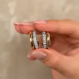 Aros tipo argolla de diseño bicolor, con una mitad en metal dorado liso y la otra mitad pavimentada con cristales brillantes.