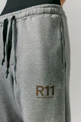 Pantalón de jogging gris de frisa con elástico ancho en cintura y puños, cordón plano ajustable, logo R11 serigrafiado y bolsillos laterales.