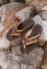 Chinelas tipo ojota con tiras de cuero en color amarillo y marrón, con base de madera y suela de goma.