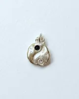 Dije de plata con diseño orgánico de Yin Yang, decorado con una piedra negra y una piedra blanca transparente.