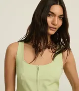 Chaleco corset de sastrería color verde claro, con escote en U, cierre frontal con cremallera, bolsillos falsos y bajo en V.