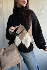 Polerón de tejido grueso con cuello alto, diseño de rombos en tonos negro, beige y blanco, y mangas largas con puños ajustados.