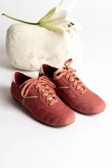 Zapatillas bajas color crema con cordones y suela marrón.