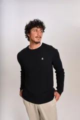 Sweater de punto con textura acanalada, color negro, de cuello redondo y manga larga. Presenta un pequeño logo bordado en el pecho.