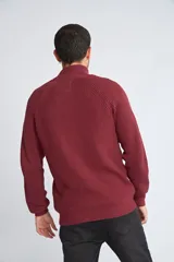 Campera tejida de algodón con cierre frontal completo, cuello alto y mangas largas con puños acanalados. Presenta un diseño de punto acanalado vertical y un pequeño logo bordado en el ruedo.