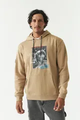 Canguro de felpa color tostado, con capucha, cordones de ajuste negros, bolsillo tipo canguro y estampado gráfico frontal inspirado en el arte clásico.