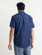 Camisa de manga corta azul con estampado de lunares blancos, cuello abotonado y bolsillo en el pecho.