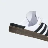 Zuecos Adidas Samba OG en color blanco con las tres tiras negras, puntera de gamuza gris y suela de goma marrón, con diseño destalonado.
