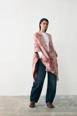 Ruana de tejido de punto con diseño teñido artesanalmente en tonos rosados y beige, con terminación de flecos en el ruedo.