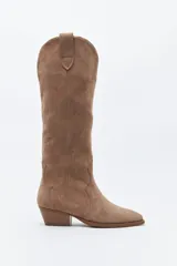 Bota texana de caña alta confeccionada en gamuza color marrón, con diseño de costuras decorativas, tirador superior y taco bajo levemente inclinado.