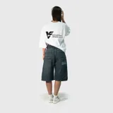 Bermuda de jean estilo baggy, color azul oscuro con efecto lavado. Presenta un corte holgado, bolsillos traseros amplios y un bordado decorativo con diseño de llamas y texto en uno de los bolsillos.