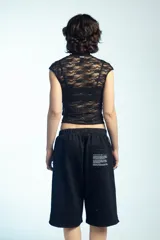 Musculosa de encaje negro con cuello alto, detalles de tiras para anudar y mangas cortas ajustadas.