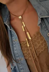 Collar tipo corbatín de cuero marrón con apliques de bronce dorado.