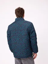 Campera reversible de nylon con cuello alto y cierre frontal. Un lado es de color gris liso con logo bordado, mientras que el otro lado presenta un estampado abstracto en tonos azules. Cuenta con bolsillos laterales y puños elásticos.