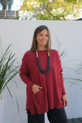 Sweater de punto color bordó, con cuello redondo, mangas largas y bolsillos frontales tipo parche. Presenta un corte holgado y diseño asimétrico con terminaciones en rib.