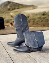 Botas de cuero color marrón y blanco con bordados negros, de estilo cowboy con taco bajo.