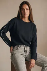 Sweater de algodón negro con calce oversize, cuello redondo y mangas largas con detalle de línea blanca lateral.