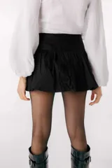 Falda corta tipo balloon color blanco, con cintura alta y diseño con volumen. Presenta una pequeña placa metálica con el logo de la marca en la parte frontal.