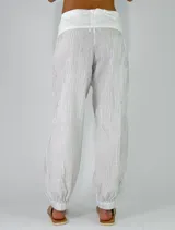 Pantalón beige con textura arrugada, de corte holgado estilo balloon con puños elásticos en los tobillos y cintura alta con faja y lazo ajustable.