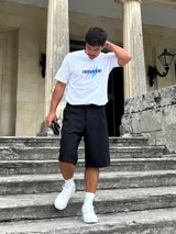 Remera blanca de algodón con estampa frontal que incluye la palabra "Brokers" en letras azules dentro de un rectángulo y dos rayos en celeste y salmón.