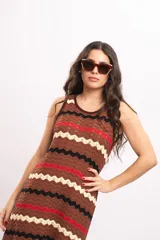 Vestido largo de tejido de punto con patrón en zigzag de rayas en tonos marrón, rojo, negro y beige, sin mangas y con escote redondo.