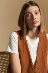 Chaleco tejido color azul, con escote en V, cierre frontal con botones y diseño de líneas verticales en relieve. Presenta terminaciones acanaladas en el ruedo y un borde ondulado en el escote.