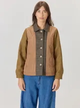 Campera de diseño combinado con frente acolchado en color tostado, mangas de lana en color verde oliva y solapa central con botones en tejido de lana a cuadros. Presenta cuello camisero y cierre frontal abotonado.