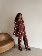 Conjunto de dos piezas compuesto por una túnica de manga larga con aberturas laterales y un pantalón de corte recto, ambos confeccionados en lanilla color marrón con estampado de lunares blancos.
