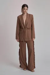 Blazer negro con solapas de muesca, corte holgado, cierre frontal con lazo y detalle de volados en los bolsillos.