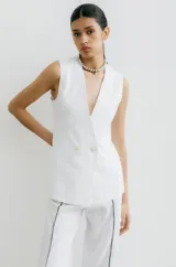 Chaleco sastrero blanco de lino, con cuello en V profundo y cierre cruzado con botones.