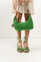 Cartera tipo shoulder bag tejida a mano con punto crochet en raffia color naranja. Tiene asa de cuero marrón y cierre superior con cremallera.