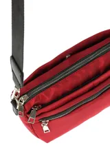 Bandolera pequeña de material sintético color beige claro, con cierre de cremallera frontal y correa ancha ajustable de tela negra.