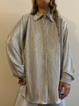 Camisa plateada plisada de manga larga con cuello camisero y cierre con botones.