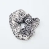 Pack de dos coleteros tipo scrunchie, uno de color beige liso con acabado satinado y otro con estampado de piel de serpiente en tonos blanco y negro.