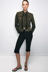 Blazer de estilo militar confeccionado en algodón, con cuello subido y manga larga. Presenta un diseño estructurado con detalle de alamares negros a contraste en el frente, botones metálicos decorativos y trabillas laterales. Cuenta con cierre frontal oculto y forro interior.