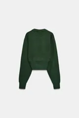 Jersey de punto liso con diseño cropped, cuello redondo y manga larga. Presenta acabados en rib en cuello, puños y bajo.