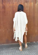 Ruana tejida de lana en color crudo, con diseño de flecos en los bordes. Es una prenda versátil y abrigada, ideal para complementar diversos looks.