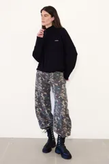 Sweater negro de punto con cuello alto y cierre frontal parcial de cremallera, de manga larga y diseño holgado con hombros caída.