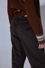 Pantalón de corte recto y tiro medio, confeccionado en tejido con patrón de cuadros oscuros. Presenta bolsillos frontales amplios y terminación con dobladillo en los tobillos.